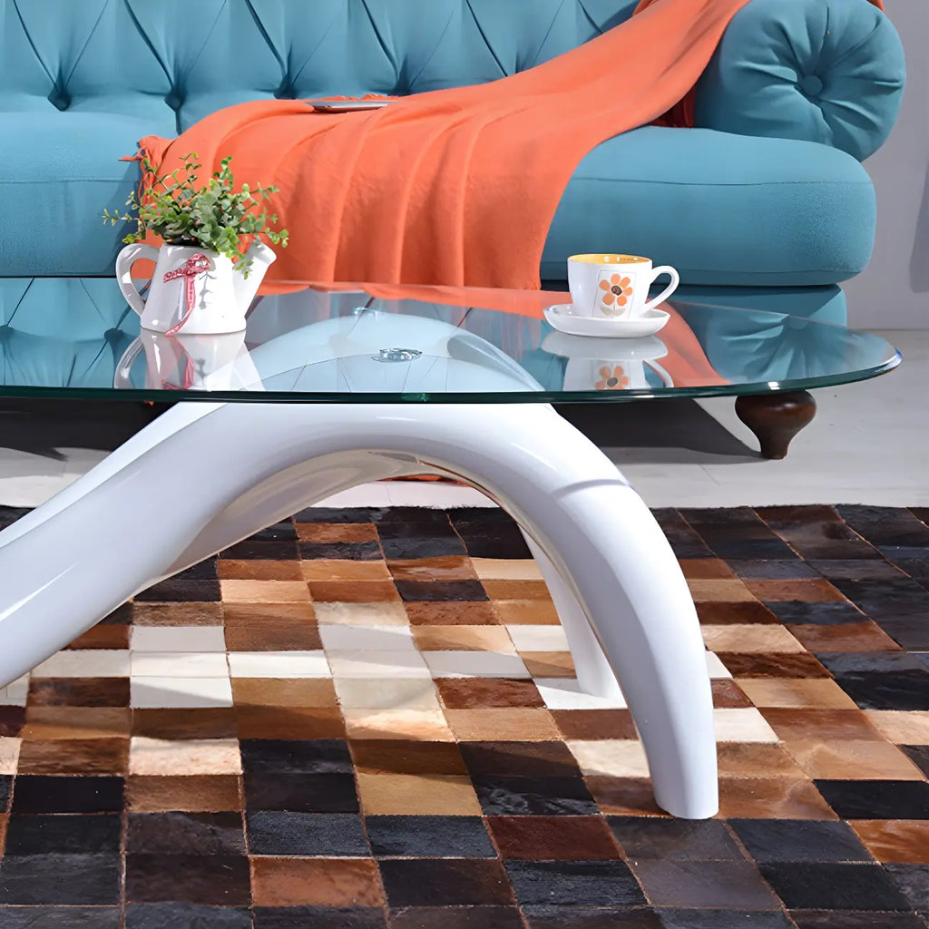 Abstracte moderne salontafel met ovaal glazen blad en metalen onderstel