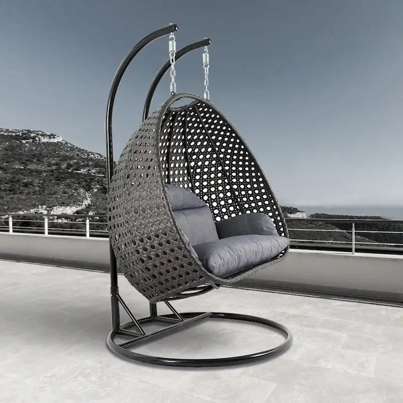LeisureMod Hängesessel in Ei-Form für 2 Personen mit Gestell - Rattan-Pendelsessel für drinnen und draußen, Hängemattensessel für die Terrasse mit Kissen